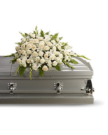 White rose and lily casket spray arranged on a silver casket