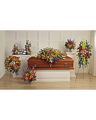 Funeral casket surrounded by bright multicolored sympathy sprays and wreaths.