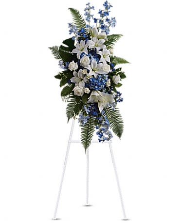 Tall white and blue standing spray with lilies and roses on a white easel