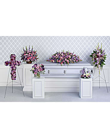 Lavender and pink funeral floral set with casket spray, cross, standing sprays and arrangements around a white casket