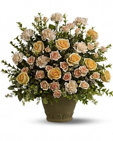 Large arrangement of peach roses and ivory carnations in a textured stone pot