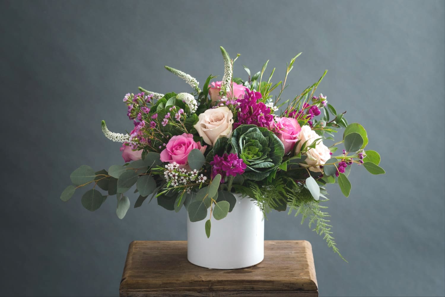 Pink and cream roses in a white vase with mixed greenery
