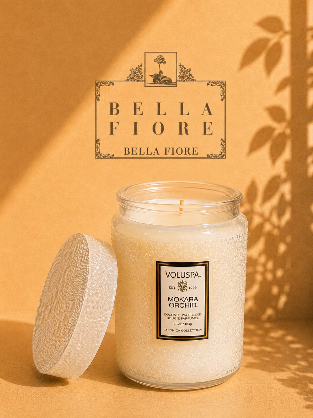 A scented candle in a textured glass jar with its lid beside it