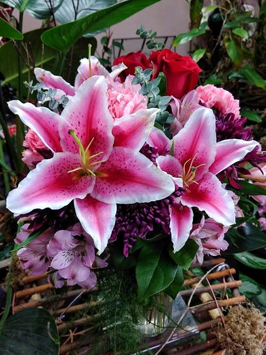 Bouquet of pink lilies and red roses in a glass vase