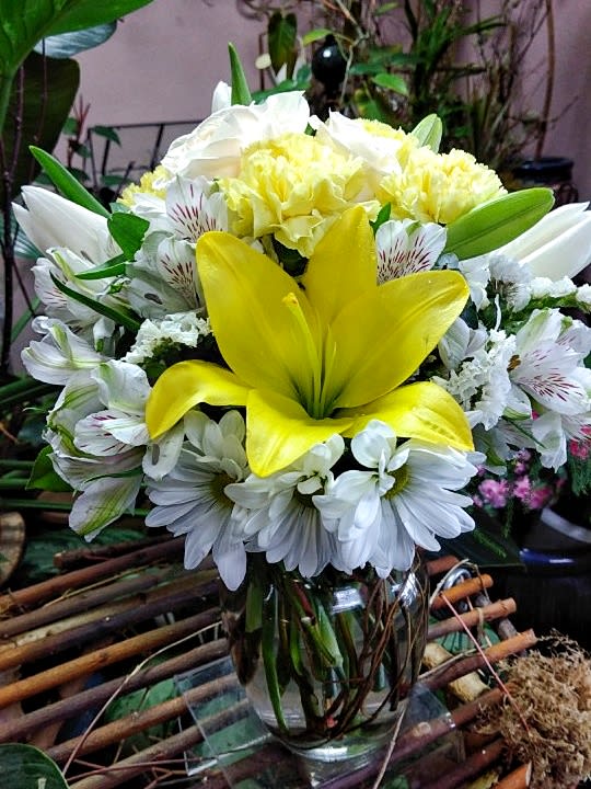 Yellow lily bouquet with white daisies in a glass vase
