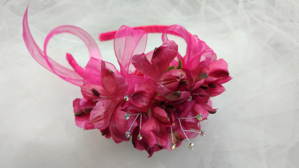 Pink floral headpiece with ribbon loops and rhinestone accents