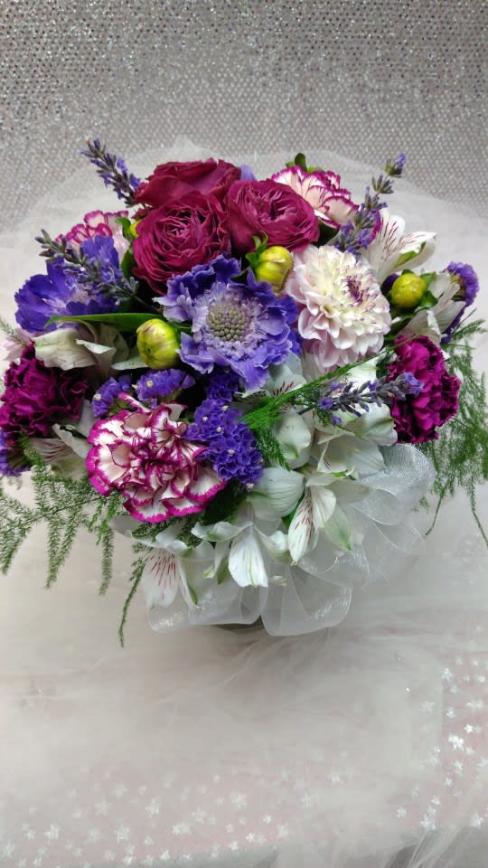 Bouquet of purple, pink, and white flowers wrapped in sheer fabric
