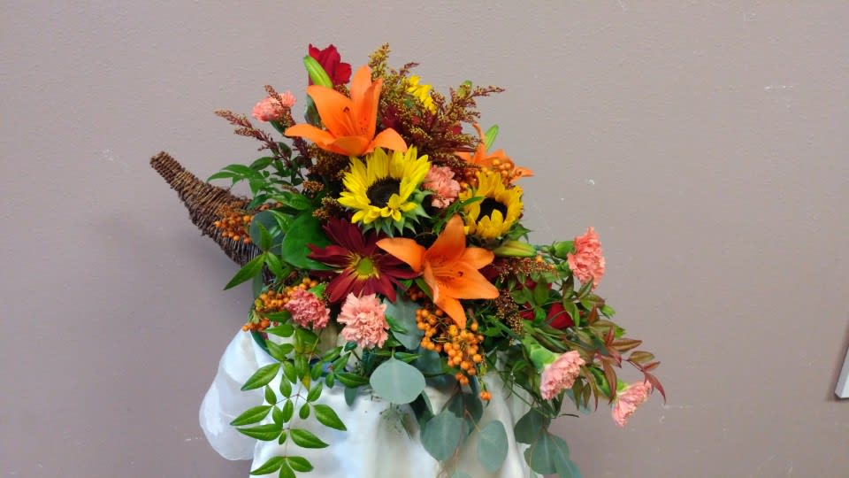 Autumn bouquet with sunflowers, lilies, and carnations in a white wrap
