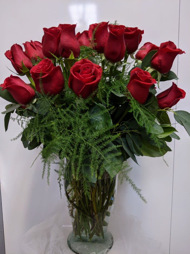 Bouquet of red roses in a glass vase with greenery