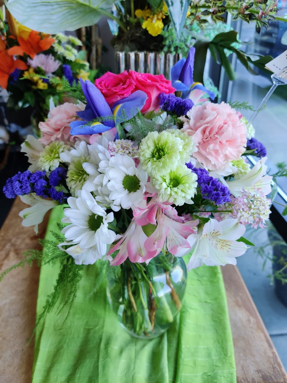 Mixed bouquet of pink, white, purple, and blue flowers in a glass vase