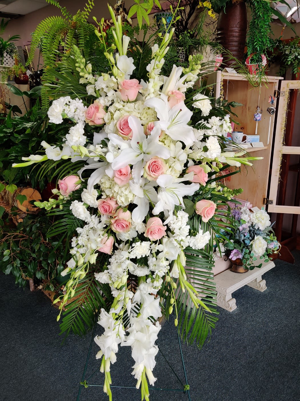 Tall standing floral spray with white lilies, pink roses, and white blooms