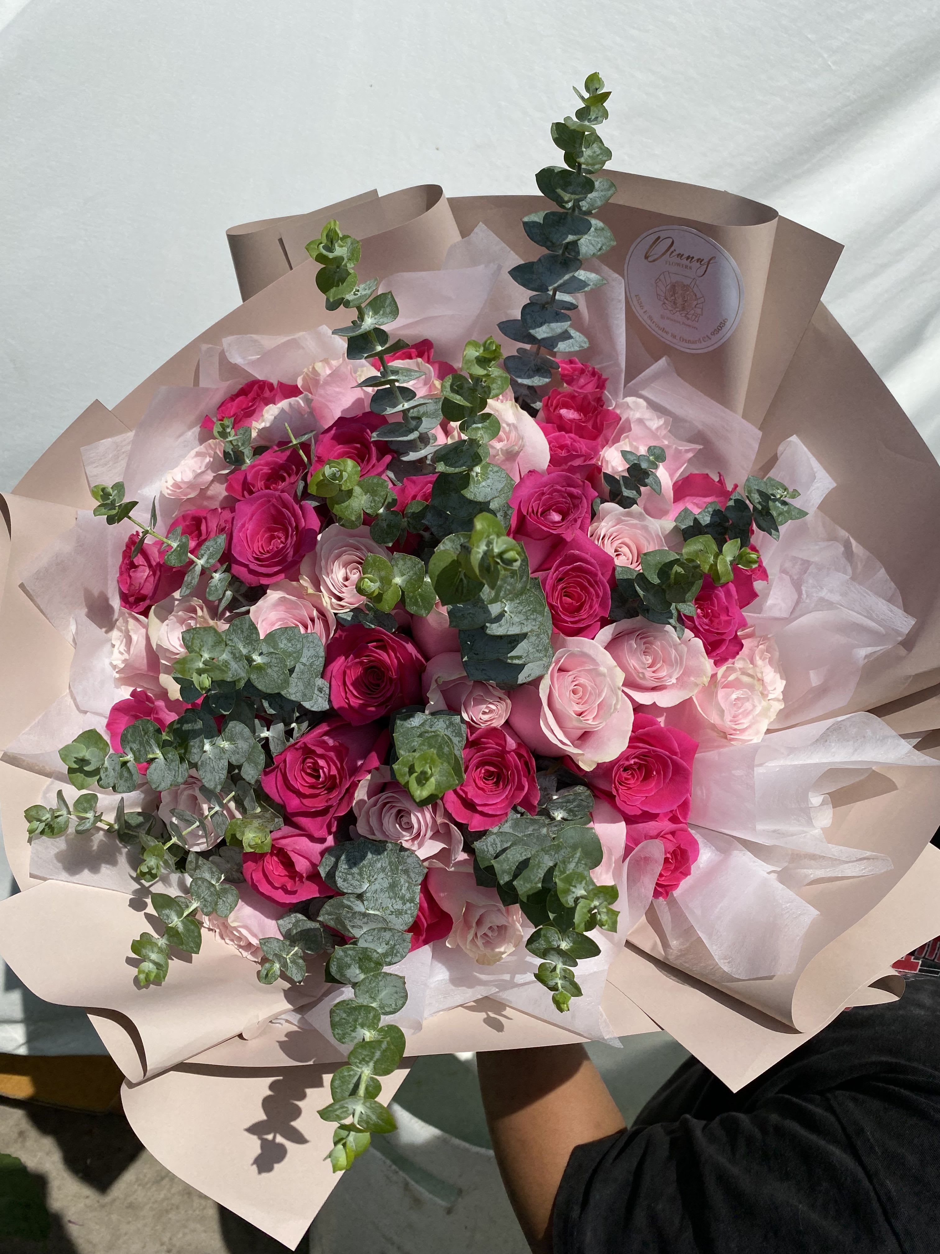 Bouquet of pink and hot pink roses with eucalyptus in blush wrapping
