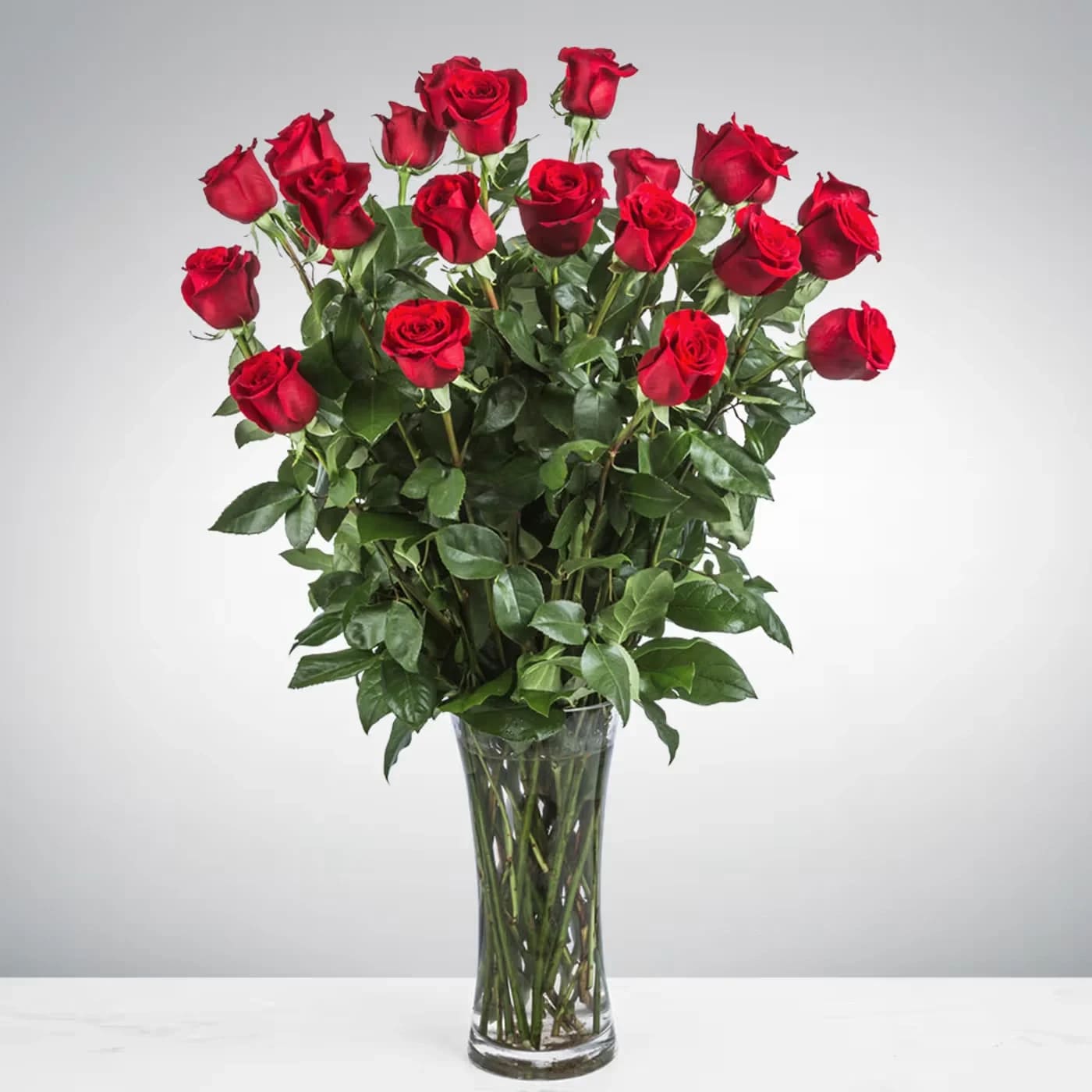 Tall bouquet of red roses in a clear glass vase