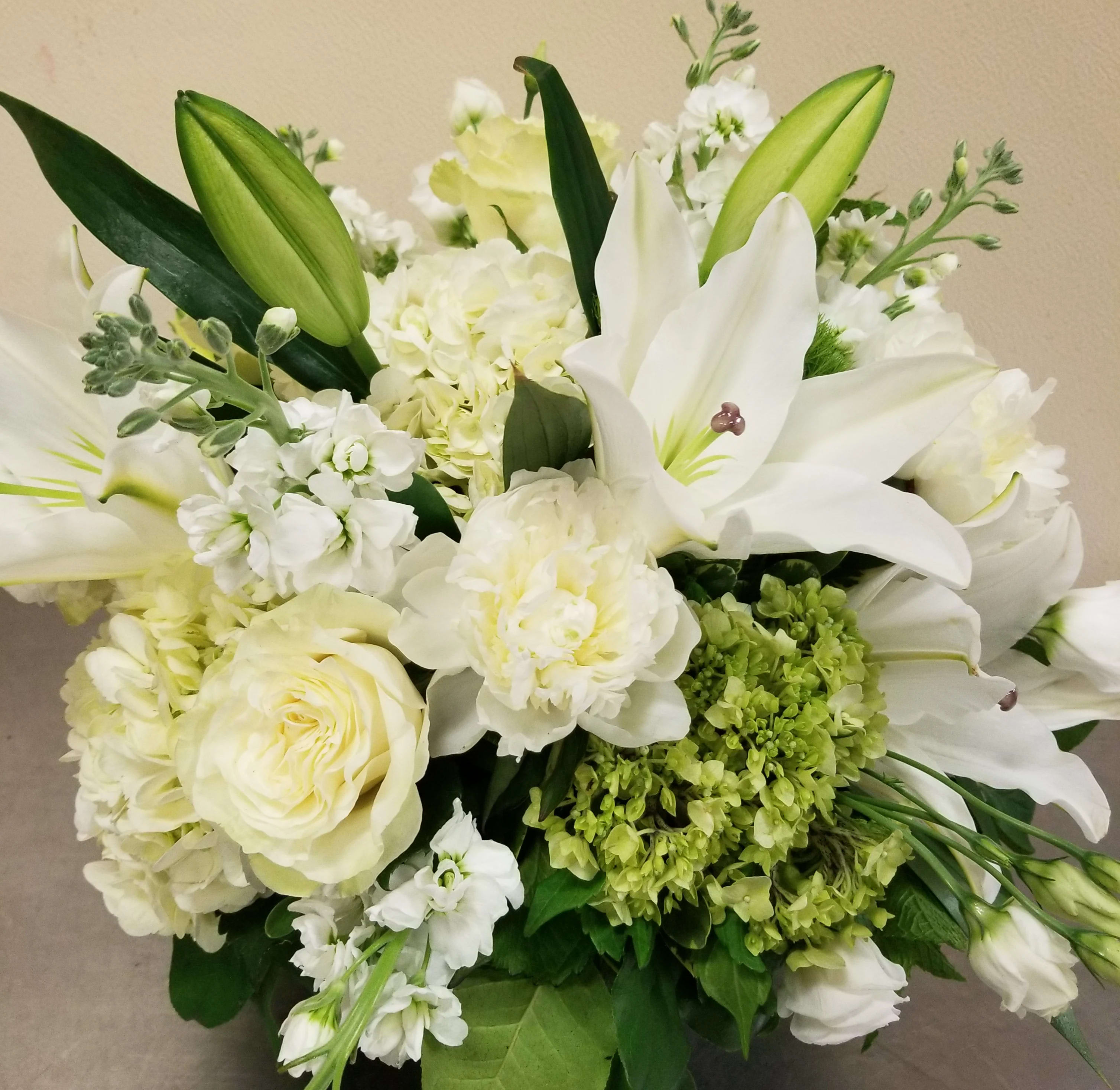 "Classic White" Bouquet - A calm, refined cluster of white and cream blooms-this Classic White bouquet is a serene flower arrangement perfect for anniversaries, sympathy and funeral tributes, or a pared-back "just because" gesture. The close, rounded composition of lilies and roses creates an immediate visual impact that reads as both elegant and comforting, making the recipient feel deeply seen and cared for.