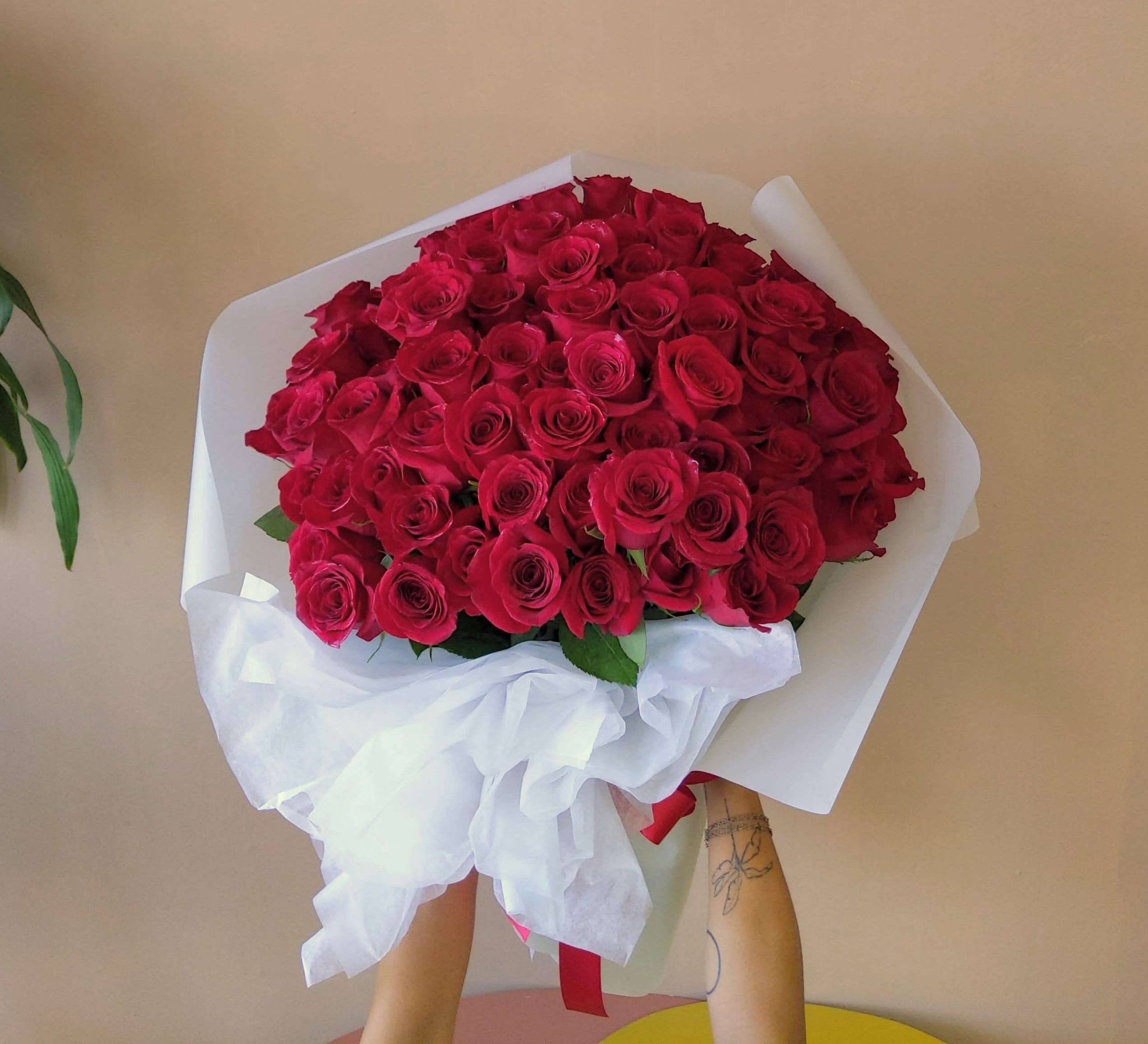 Large bouquet of red roses wrapped in white paper with a ribbon