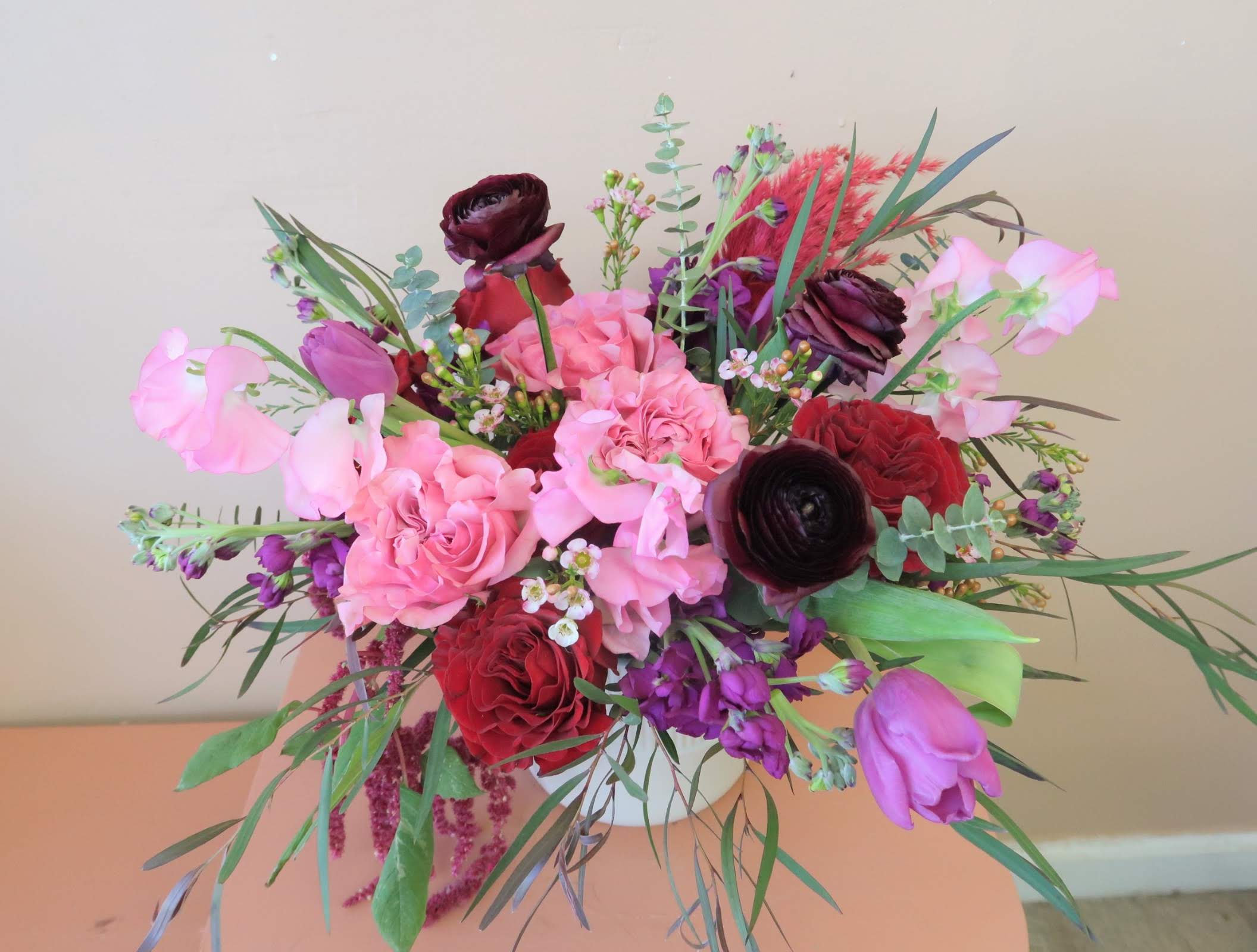 Mixed bouquet of pink, red, and purple flowers with greenery