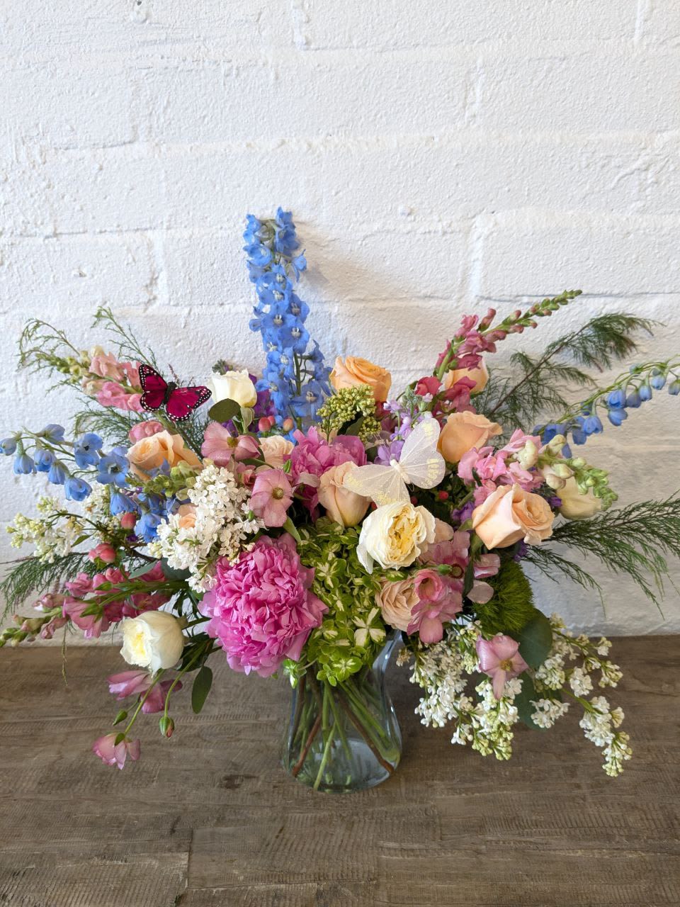 Mixed bouquet in a glass vase with pink, peach, white, and blue flowers