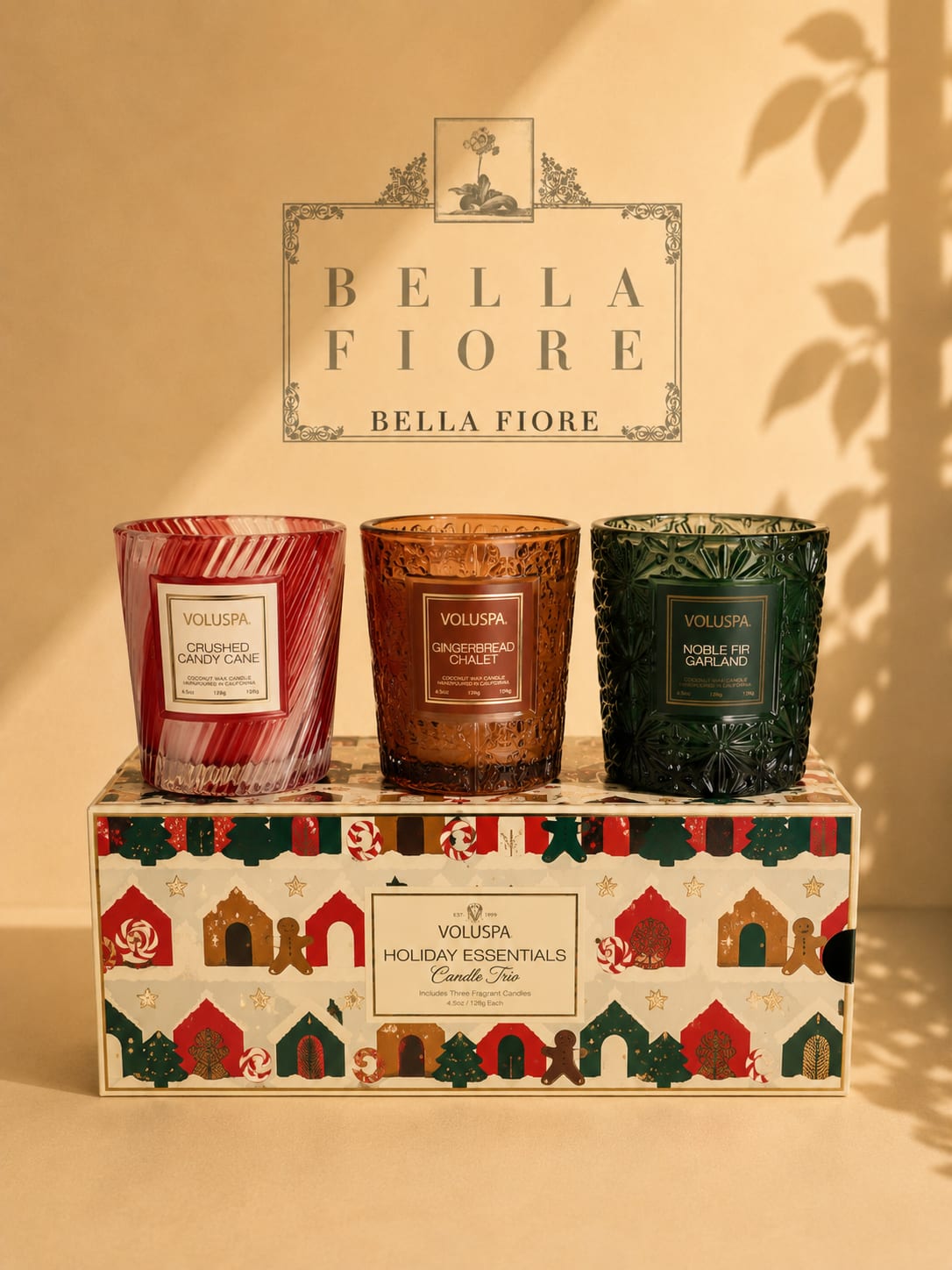 Three scented candles in decorative glass holders on a holiday gift box