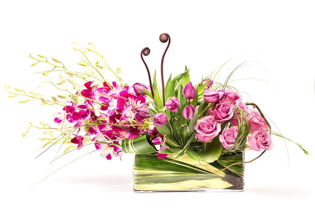 Pink roses and orchids in a rectangular glass vase