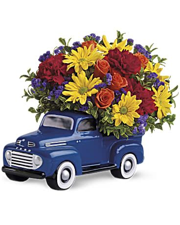 Blue truck figurine filled with colorful flowers