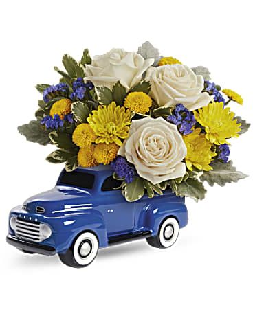 Blue toy truck holding white roses and yellow flowers
