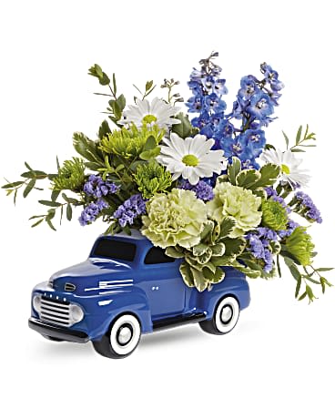 Blue toy truck filled with white, blue, and green flowers