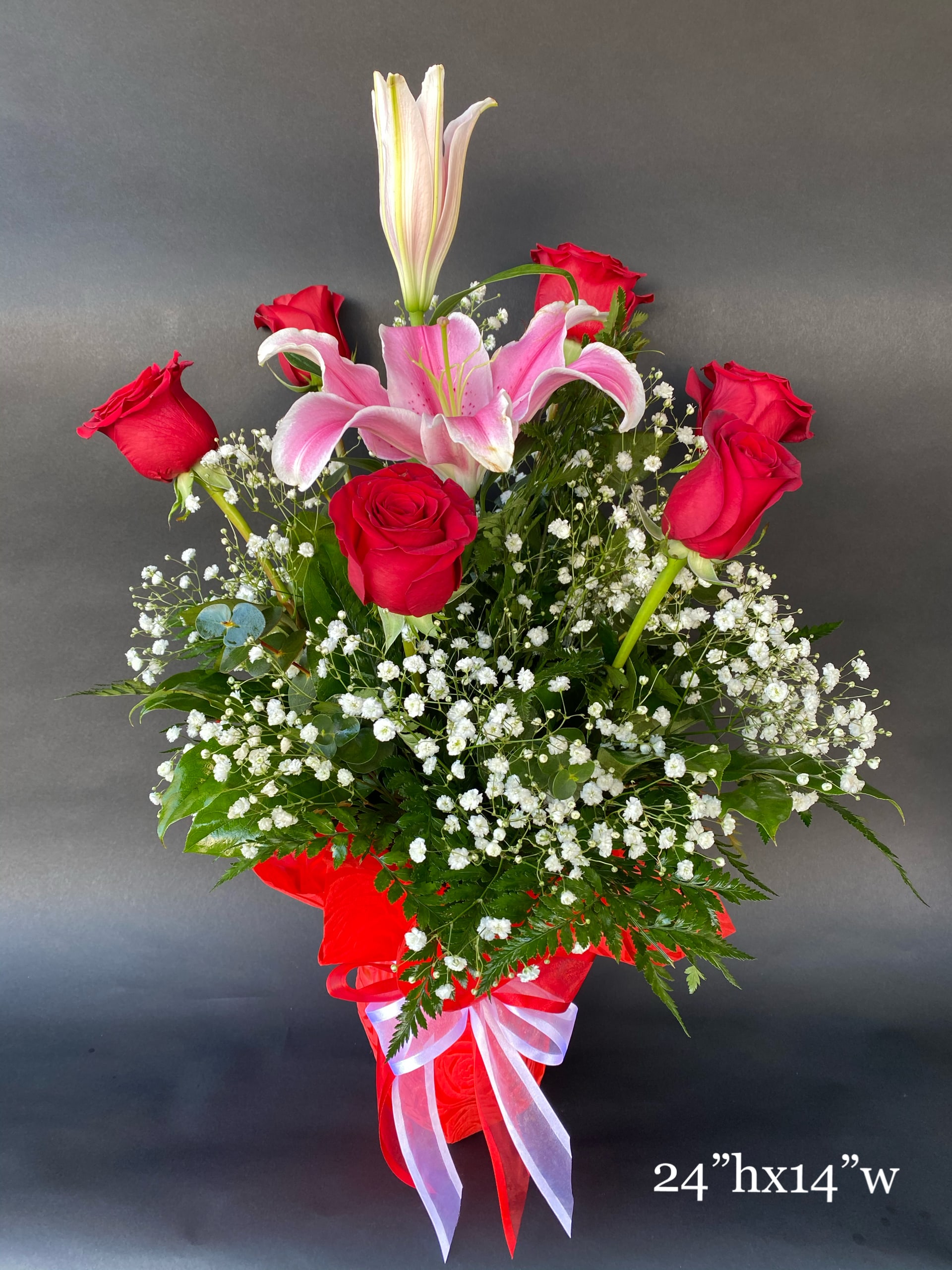 Red roses and pink lilies in a red ribboned vase arrangement