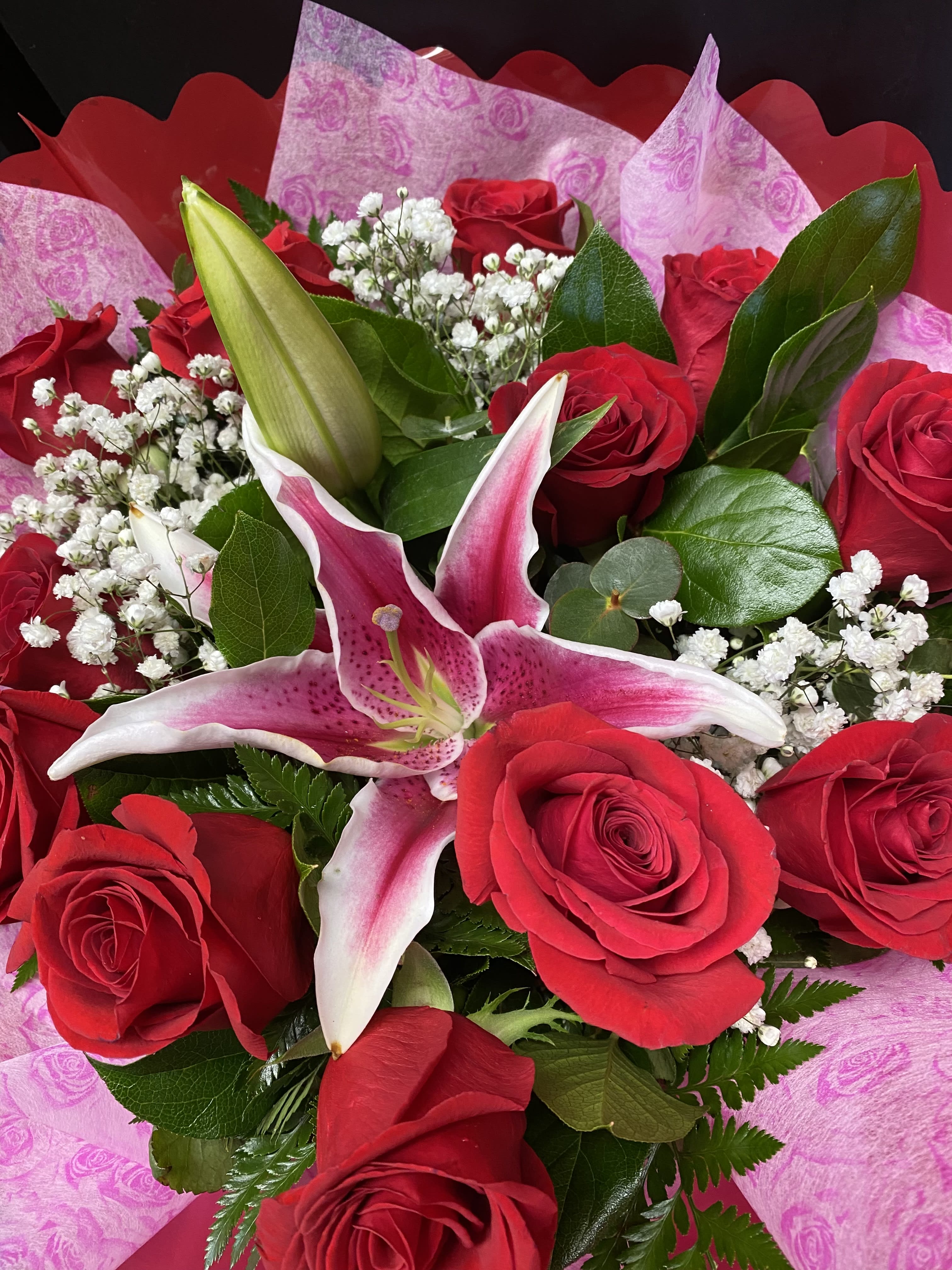 Bouquet of red roses and a pink lily with white filler flowers