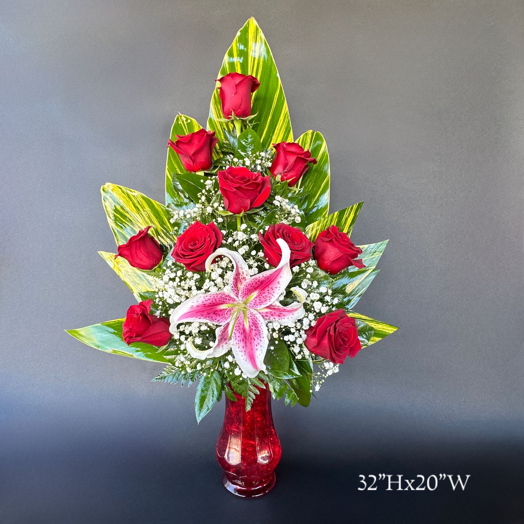 Red roses and a pink lily in a red vase
