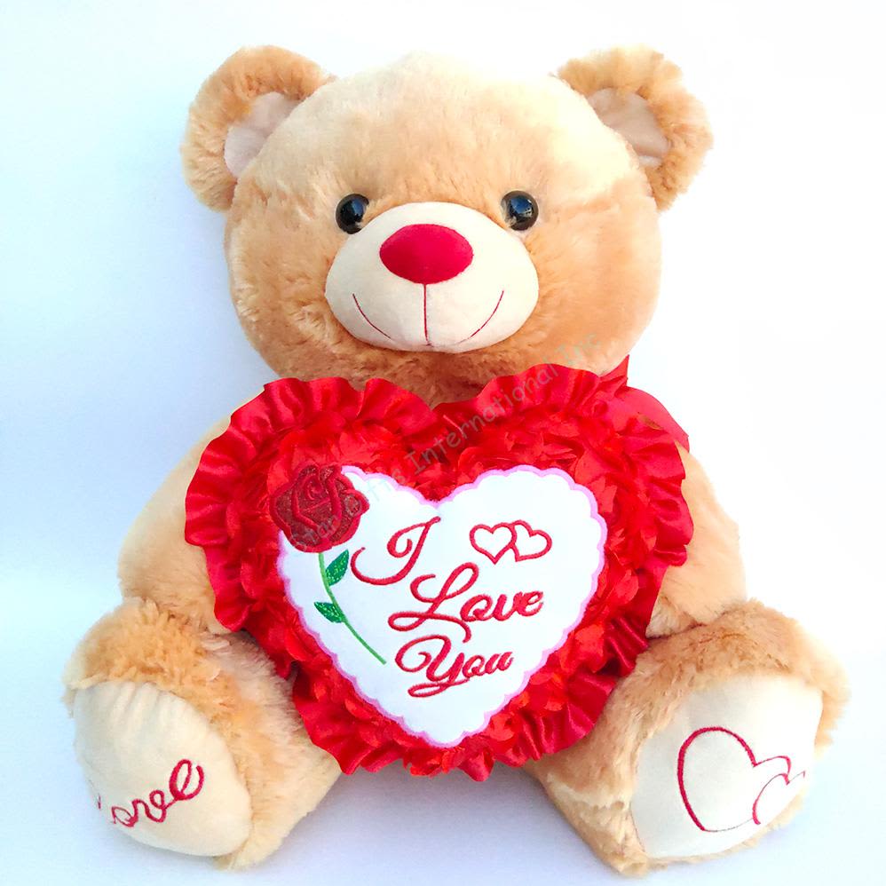 Plush teddy bear holding a heart-shaped "I Love You" pillow