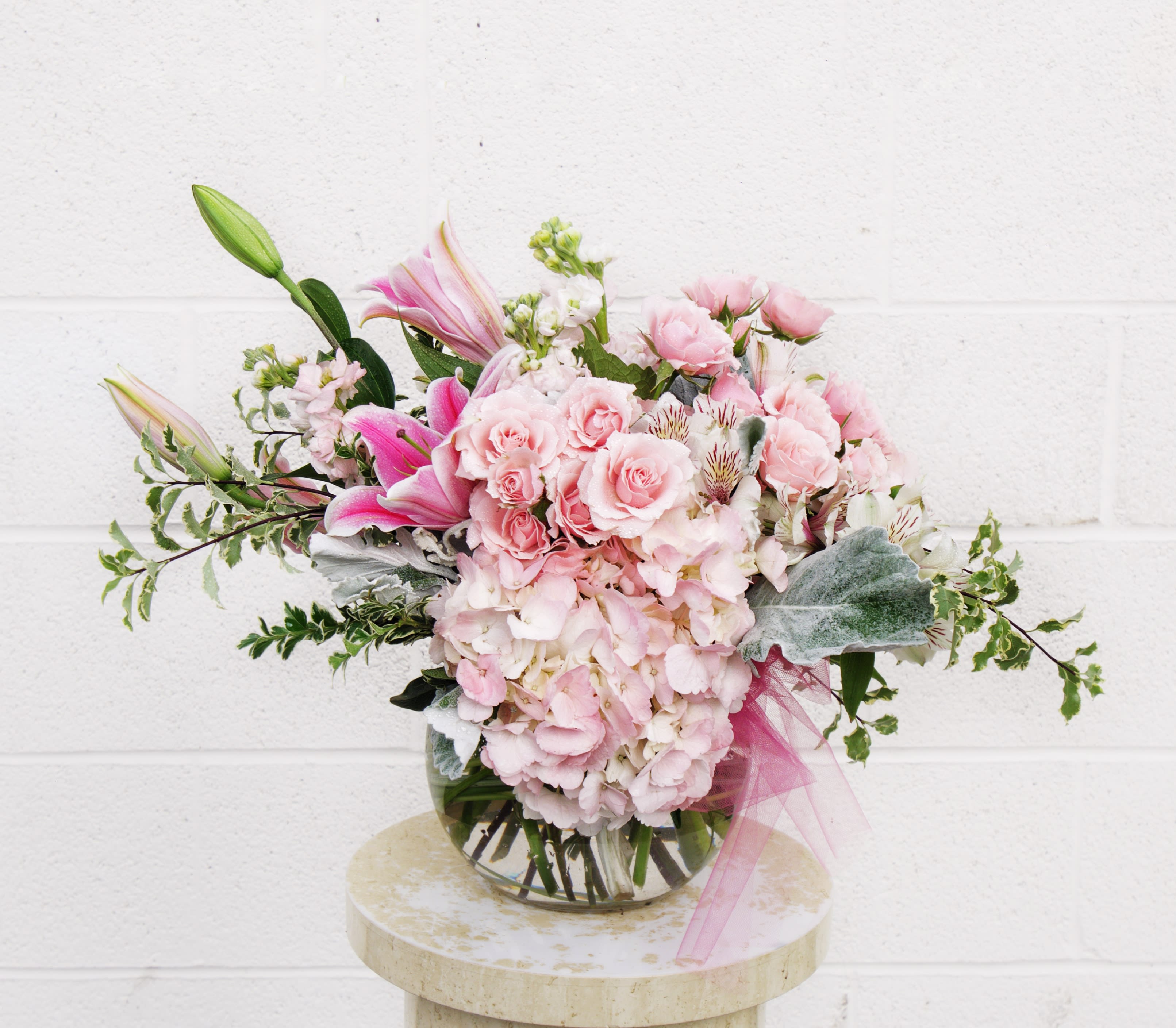 Pink roses and lilies arranged in a glass vase