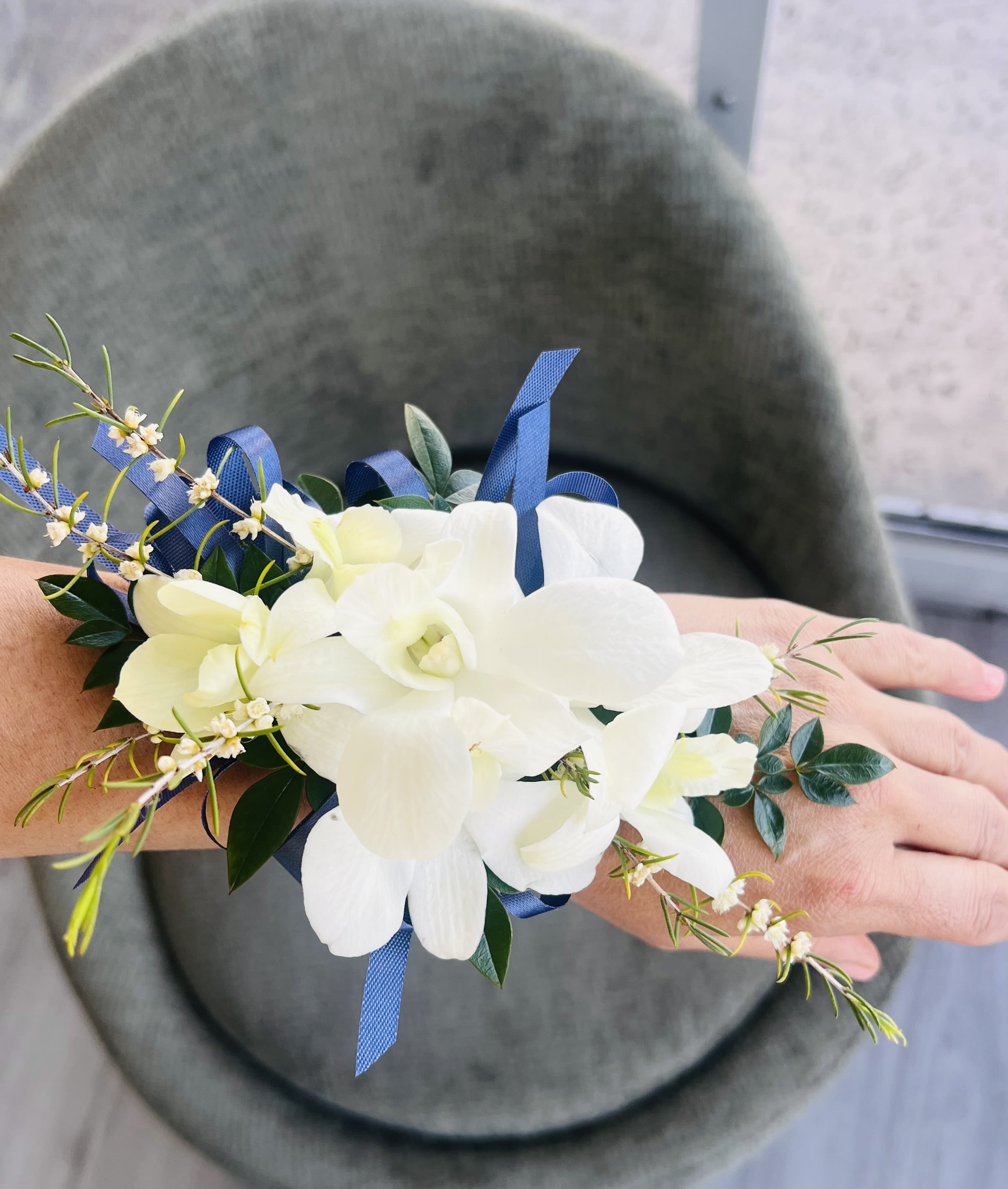 White orchid wrist corsage with blue ribbon accents