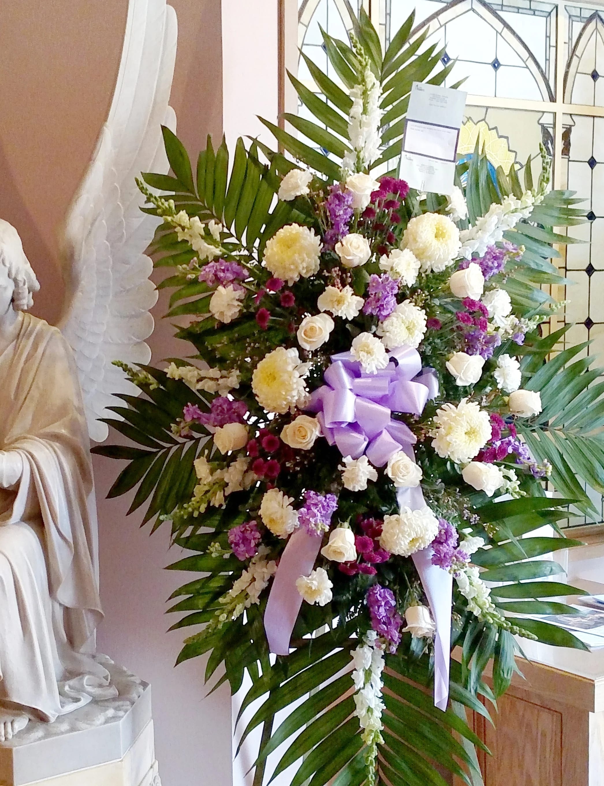 Large standing floral spray with white and purple flowers and a lavender ribbon