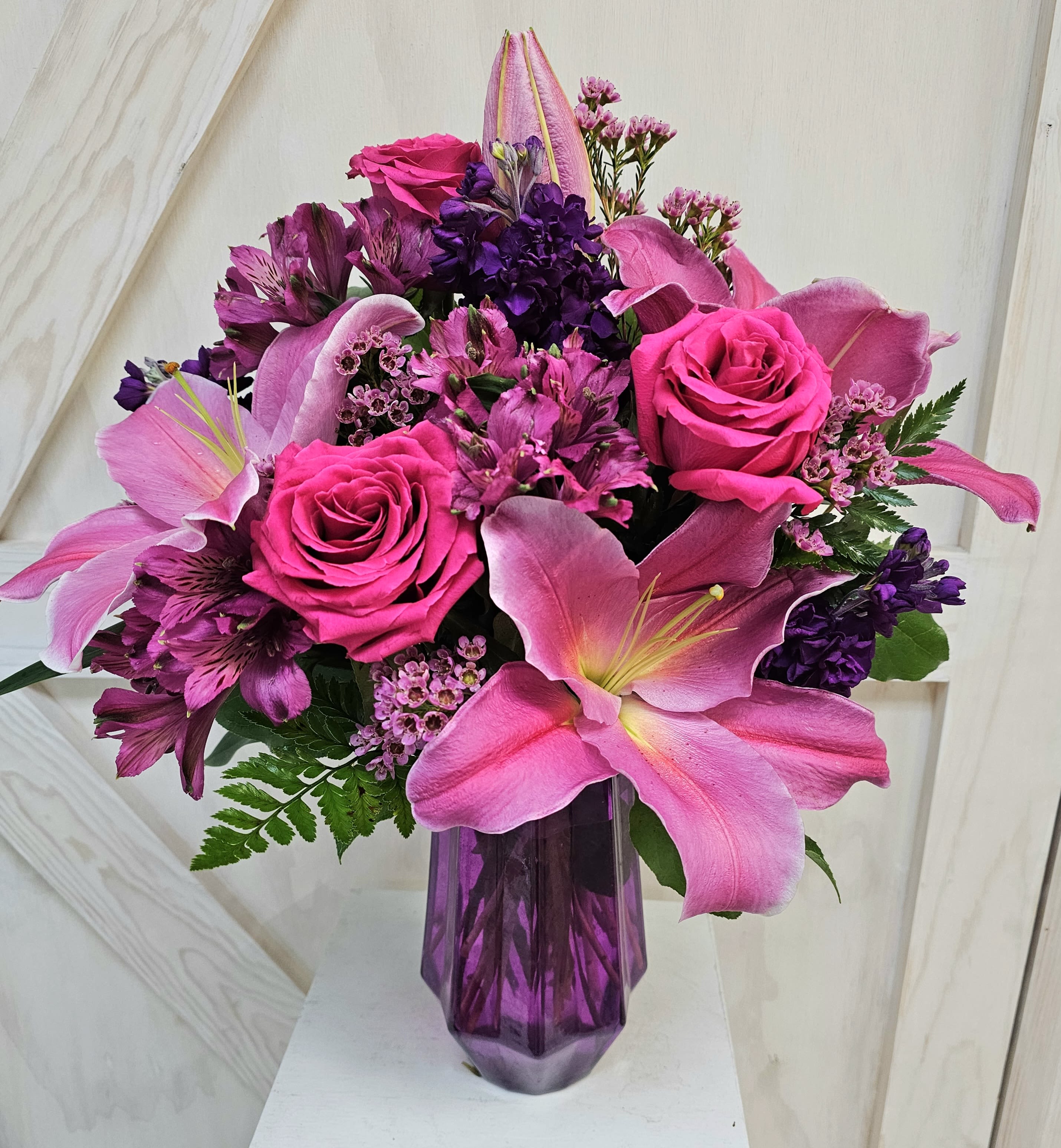 Pink and purple bouquet with roses and lilies in a purple vase