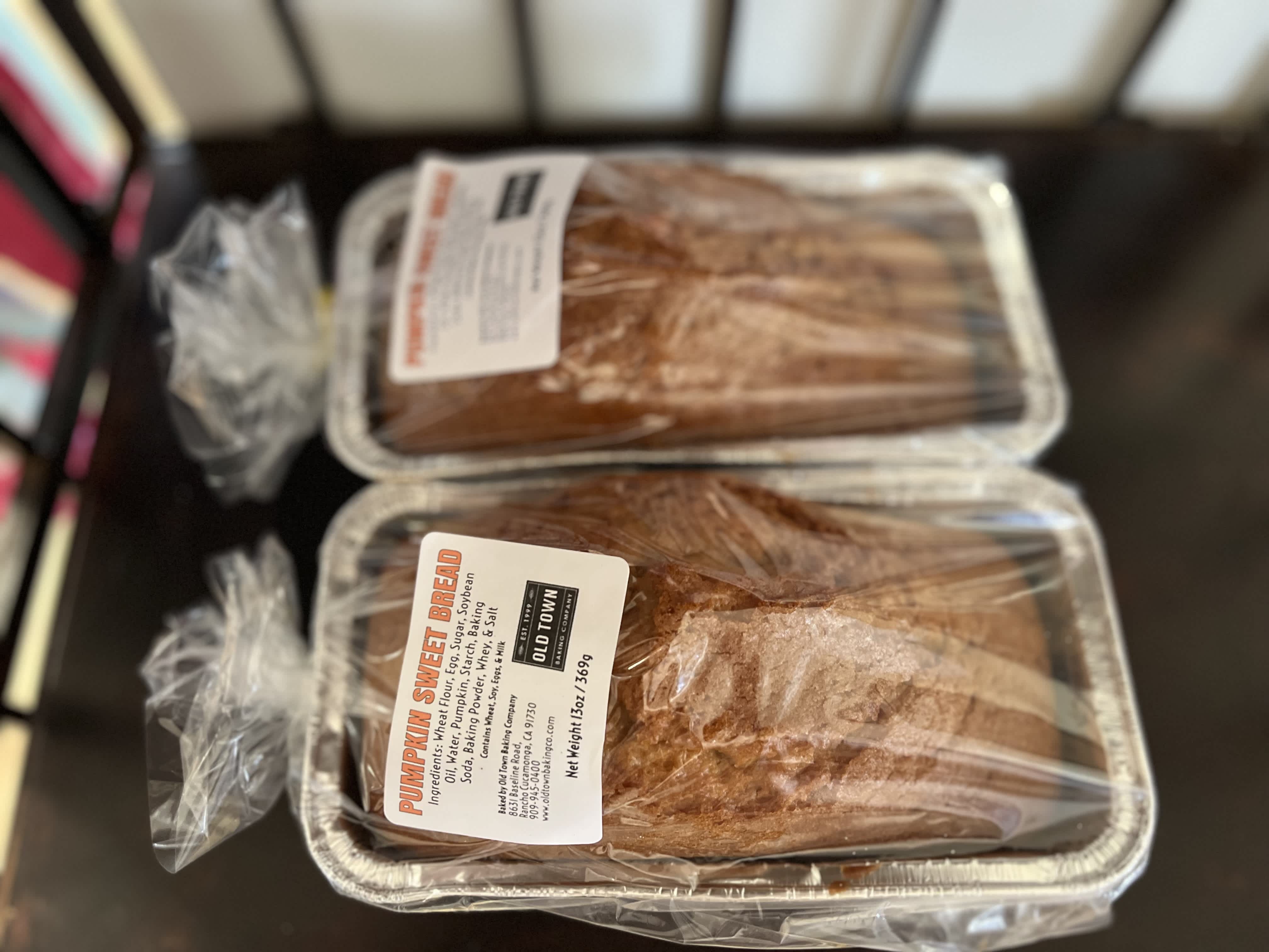 Two wrapped loaves of pumpkin sweet bread in foil pans