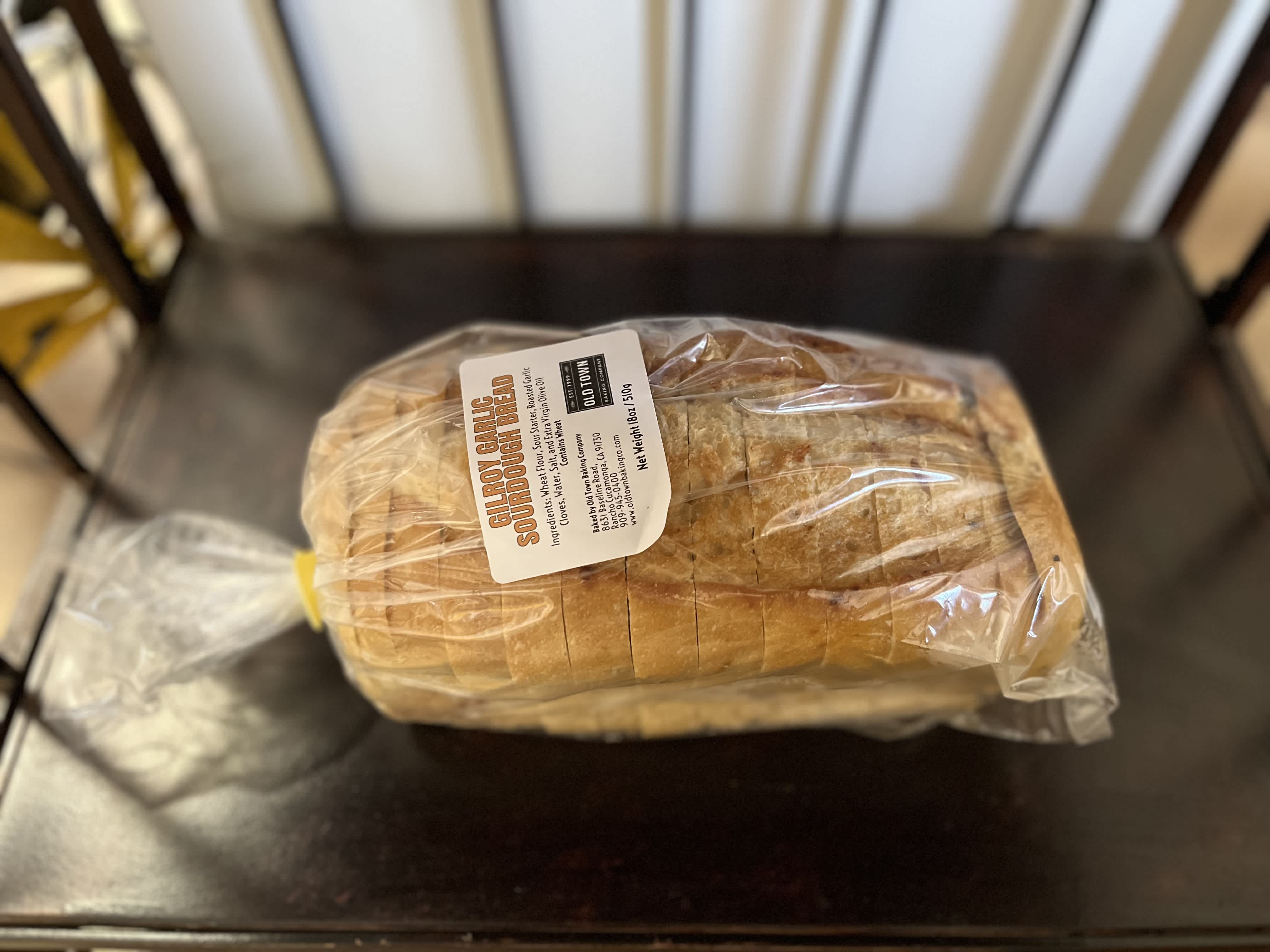 Wrapped loaf of sourdough bread on a dark table