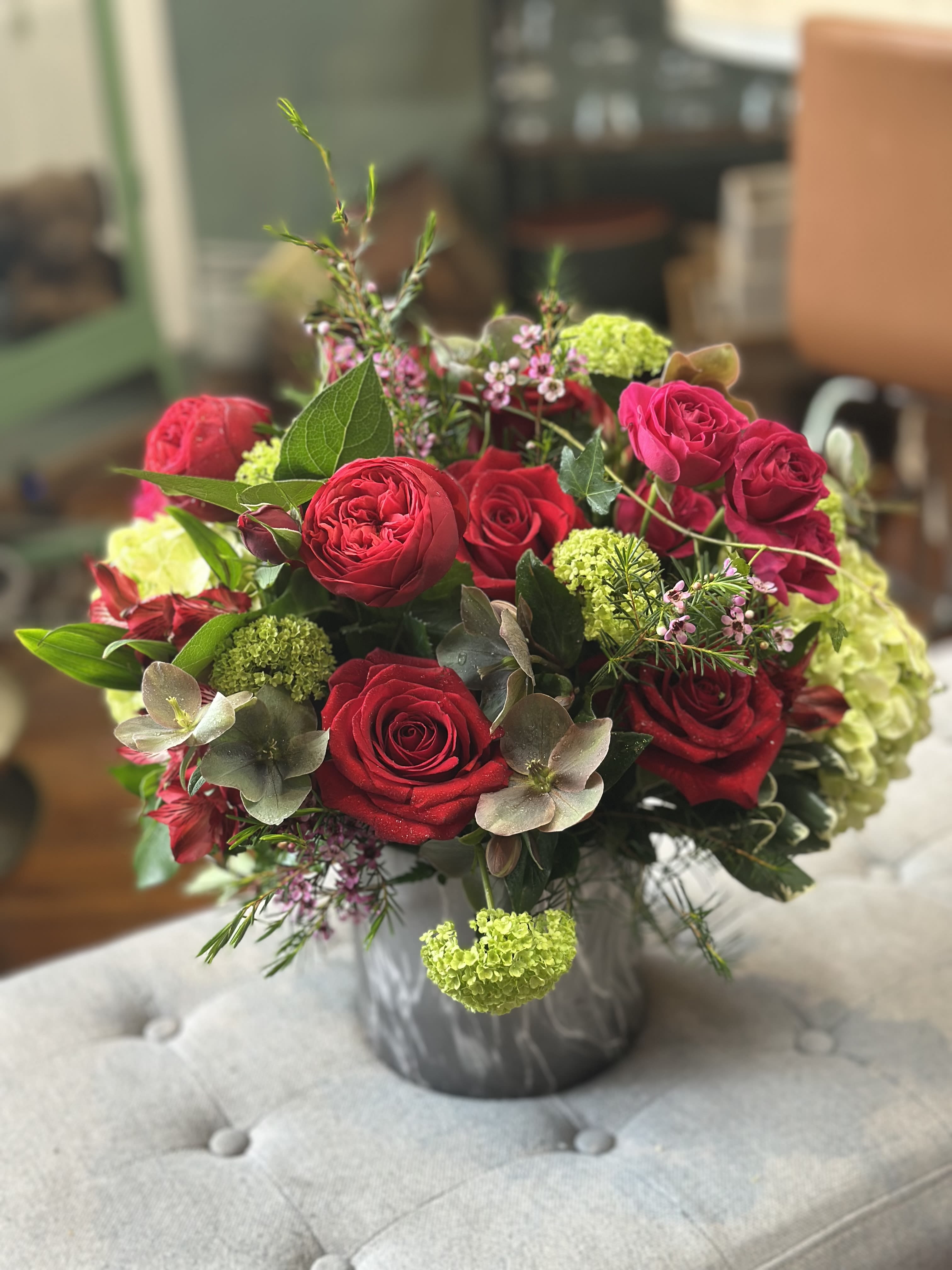 Round arrangement of red roses with green hydrangea in a gray marbled vase