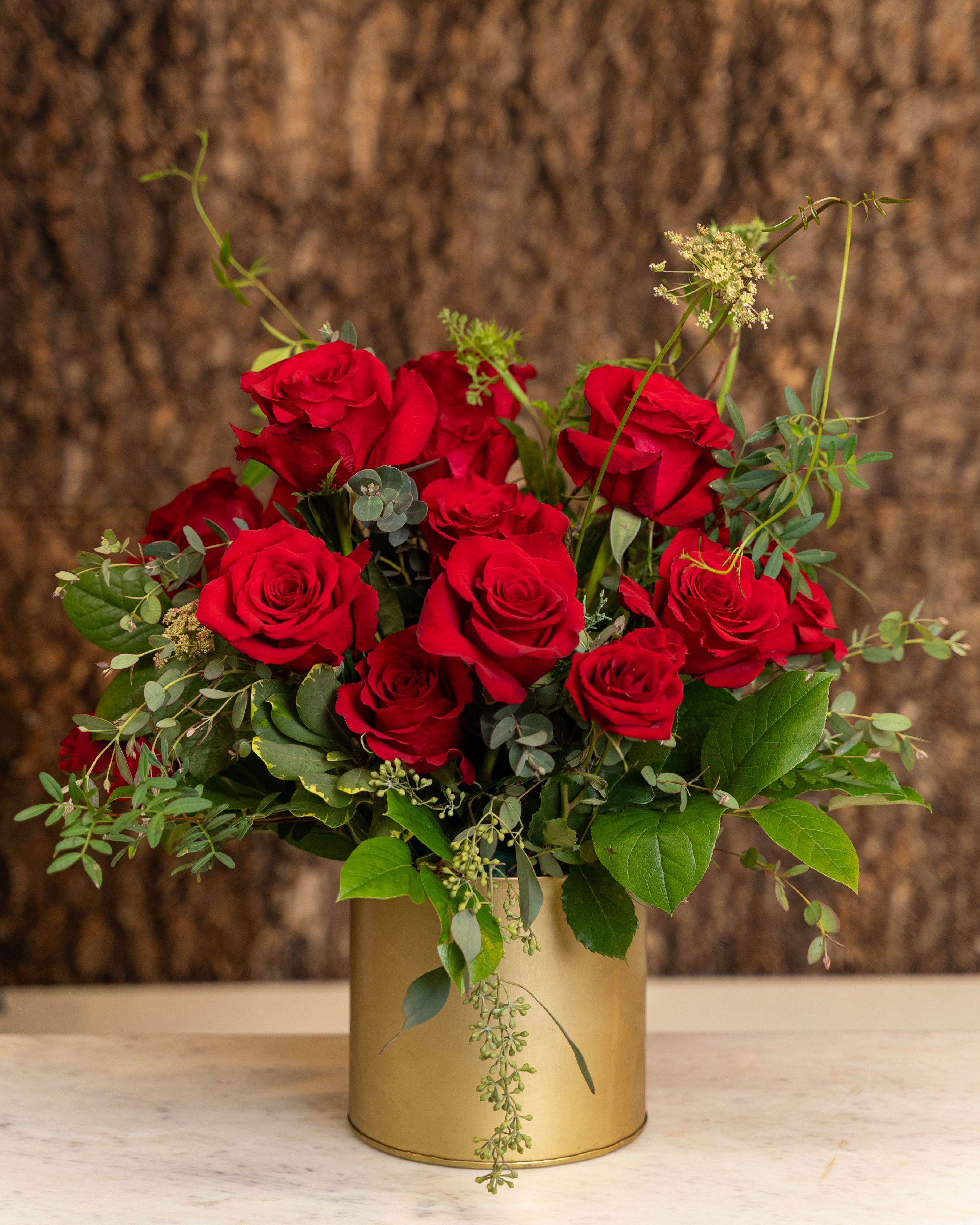 Arrangement of red roses in a gold cylinder vase on a marble surface