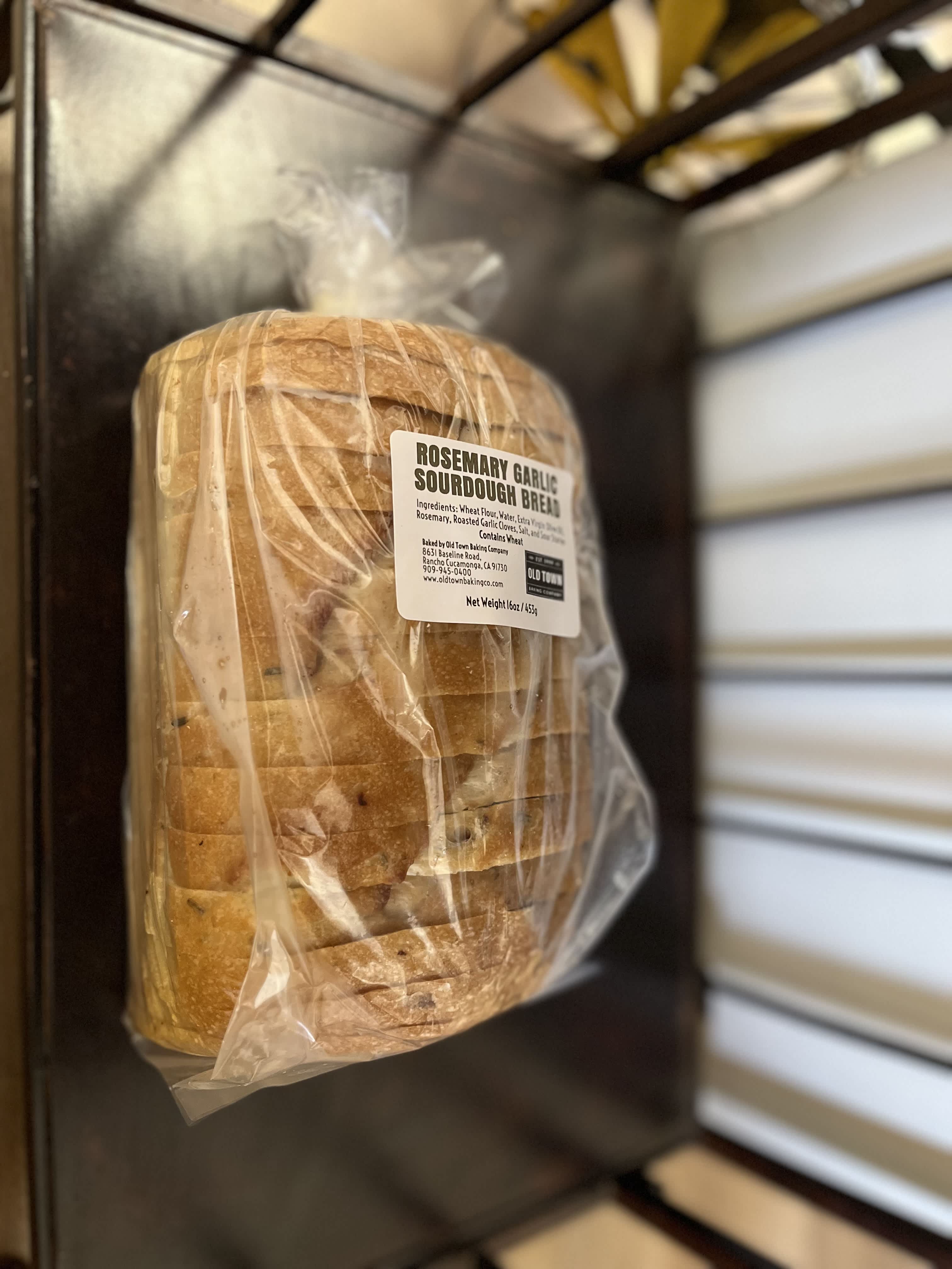 Wrapped loaf of rosemary garlic sourdough bread with a product label