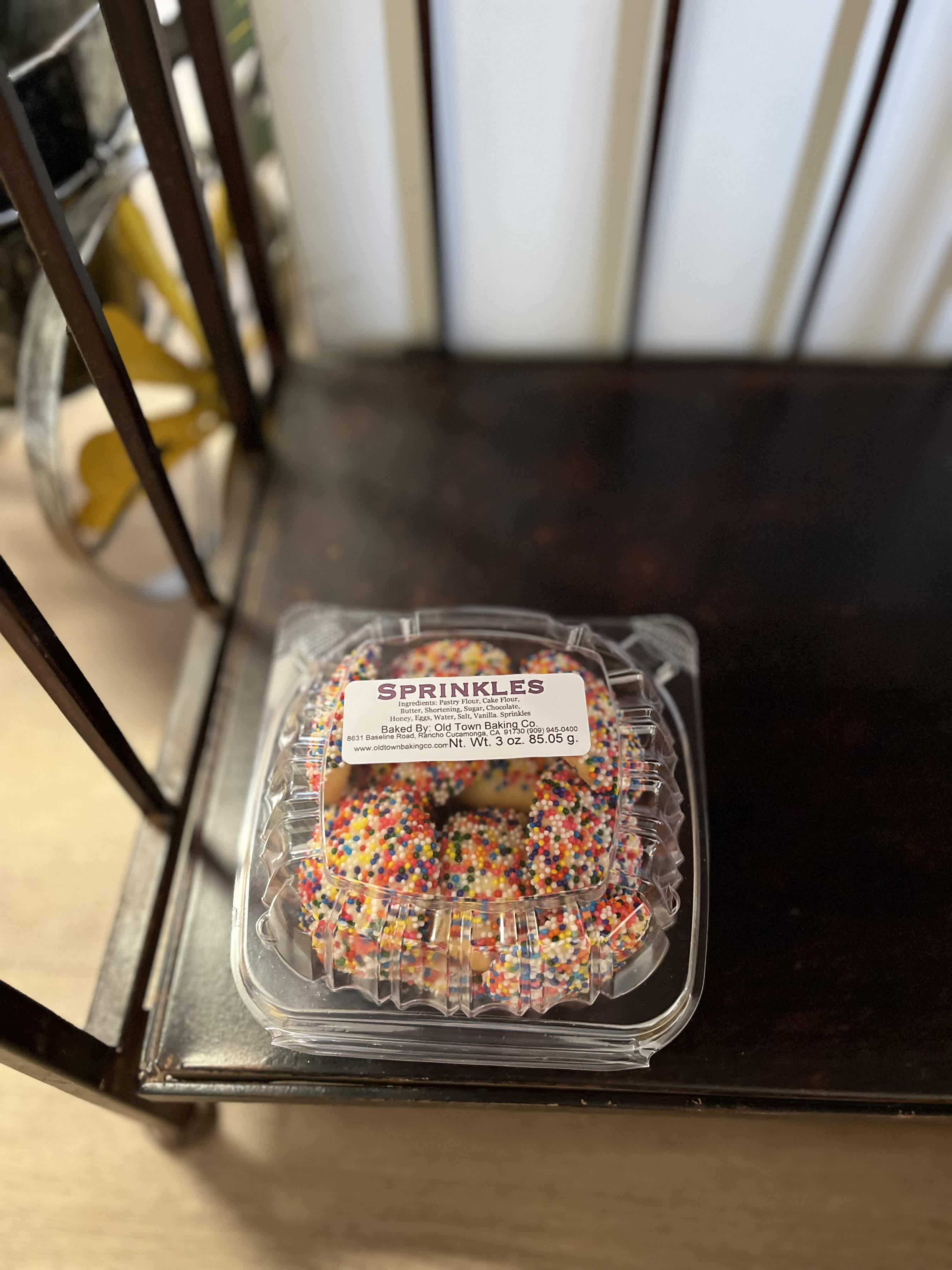 Plastic clamshell container of sprinkle-covered cookies on a chair