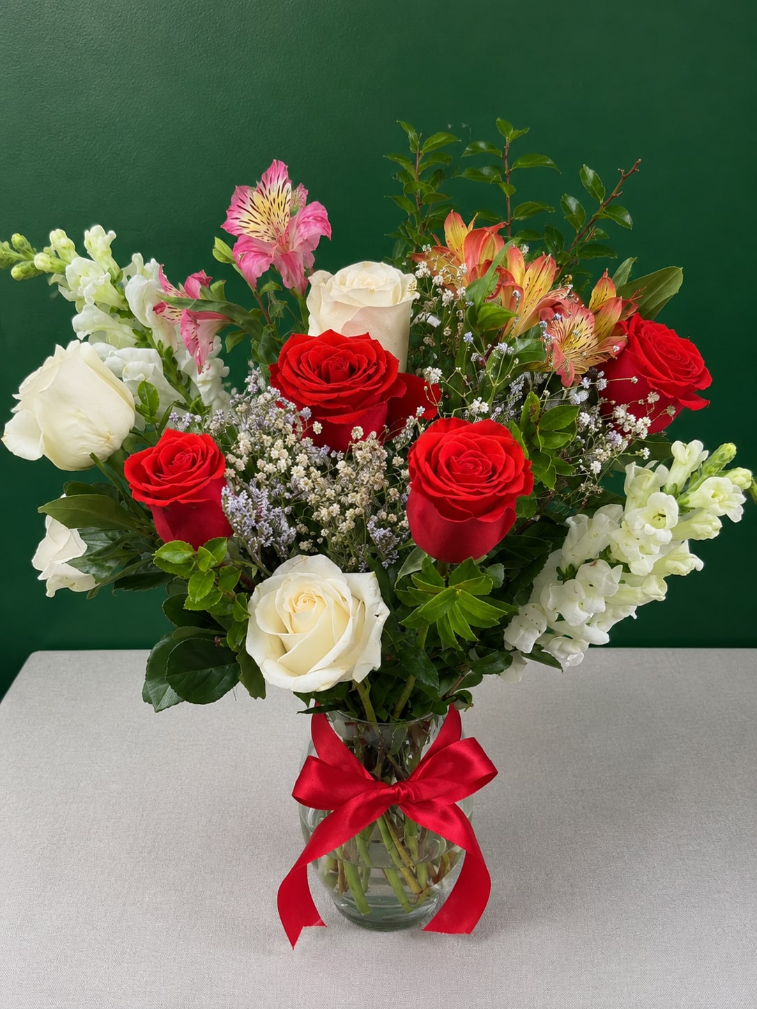 Bouquet of red and white roses with pink alstroemeria in a glass vase