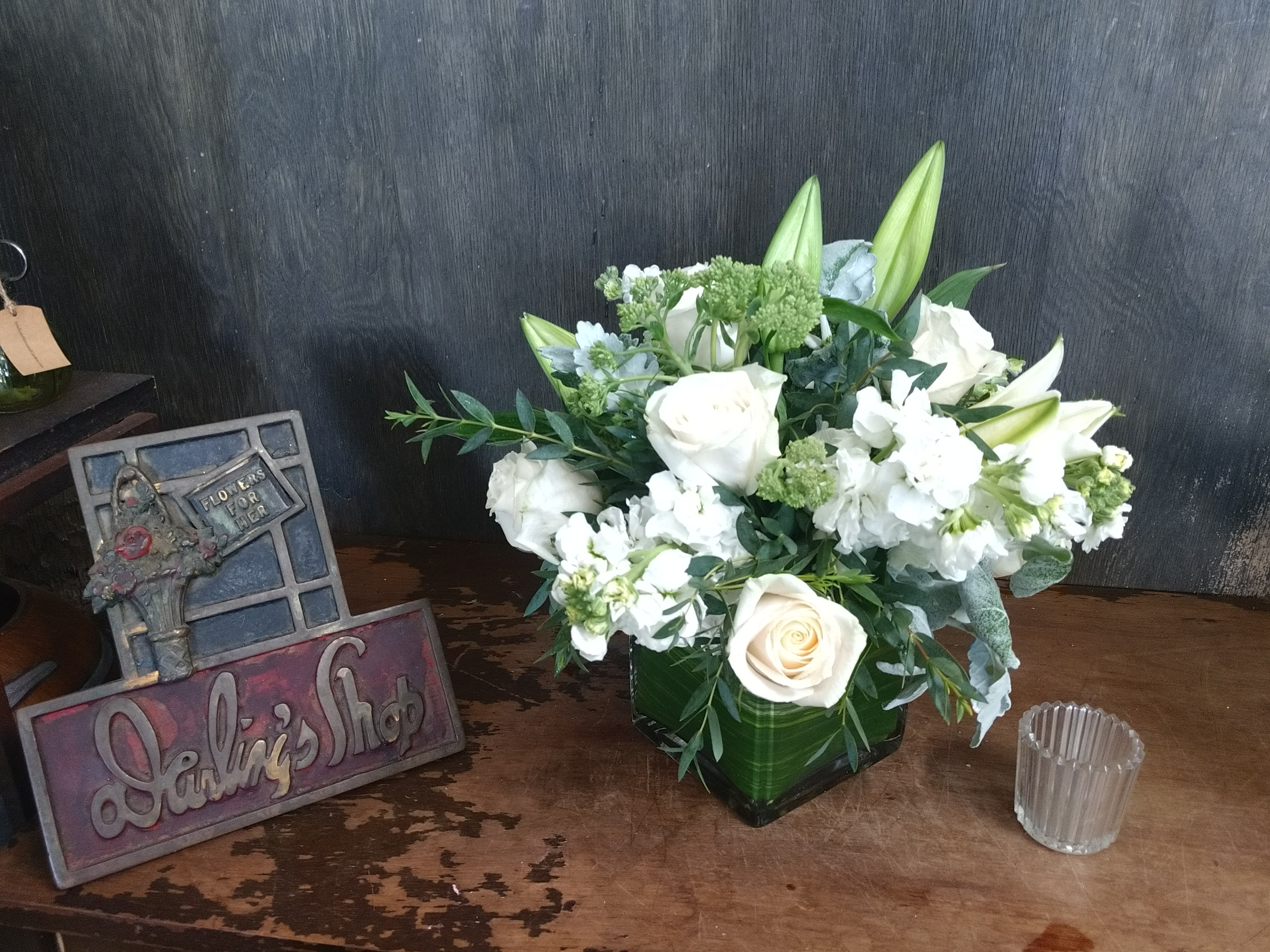 White roses and lilies arranged in a green vase.