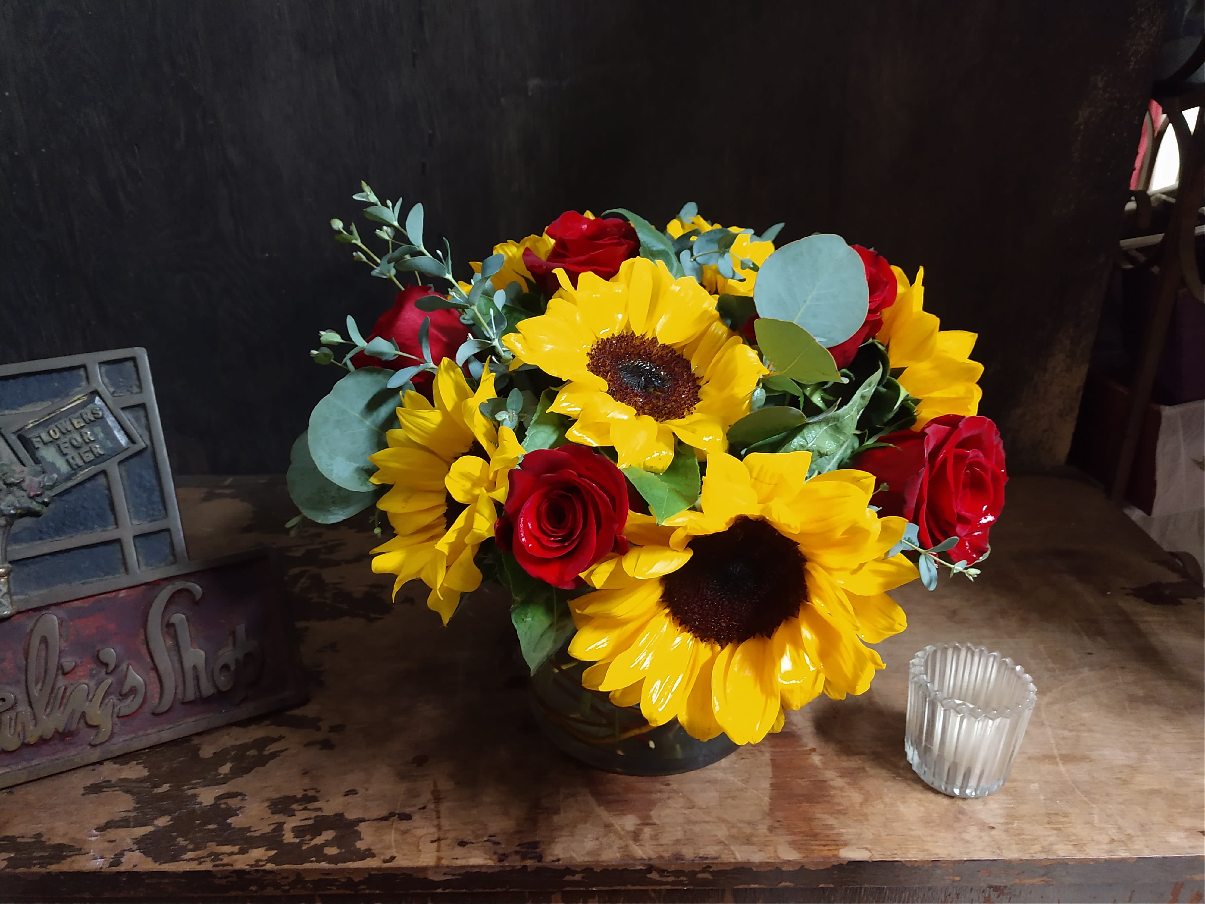 Bouquet of yellow sunflowers and red roses in a dark vase