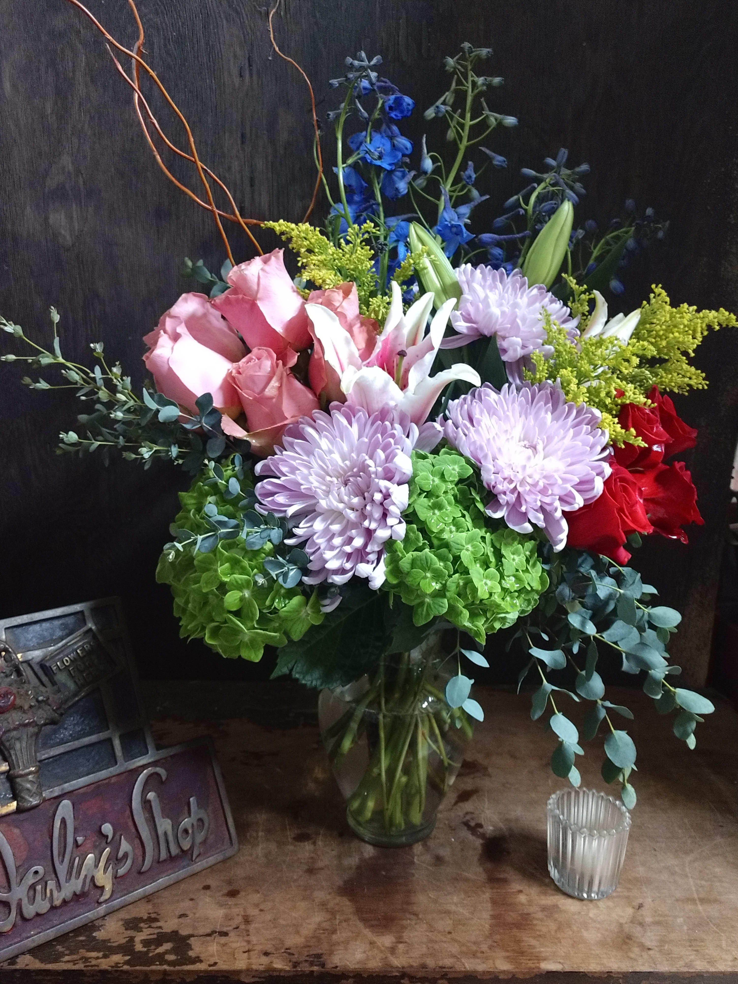 Mixed bouquet in a glass vase with pink roses, lavender mums, and lilies