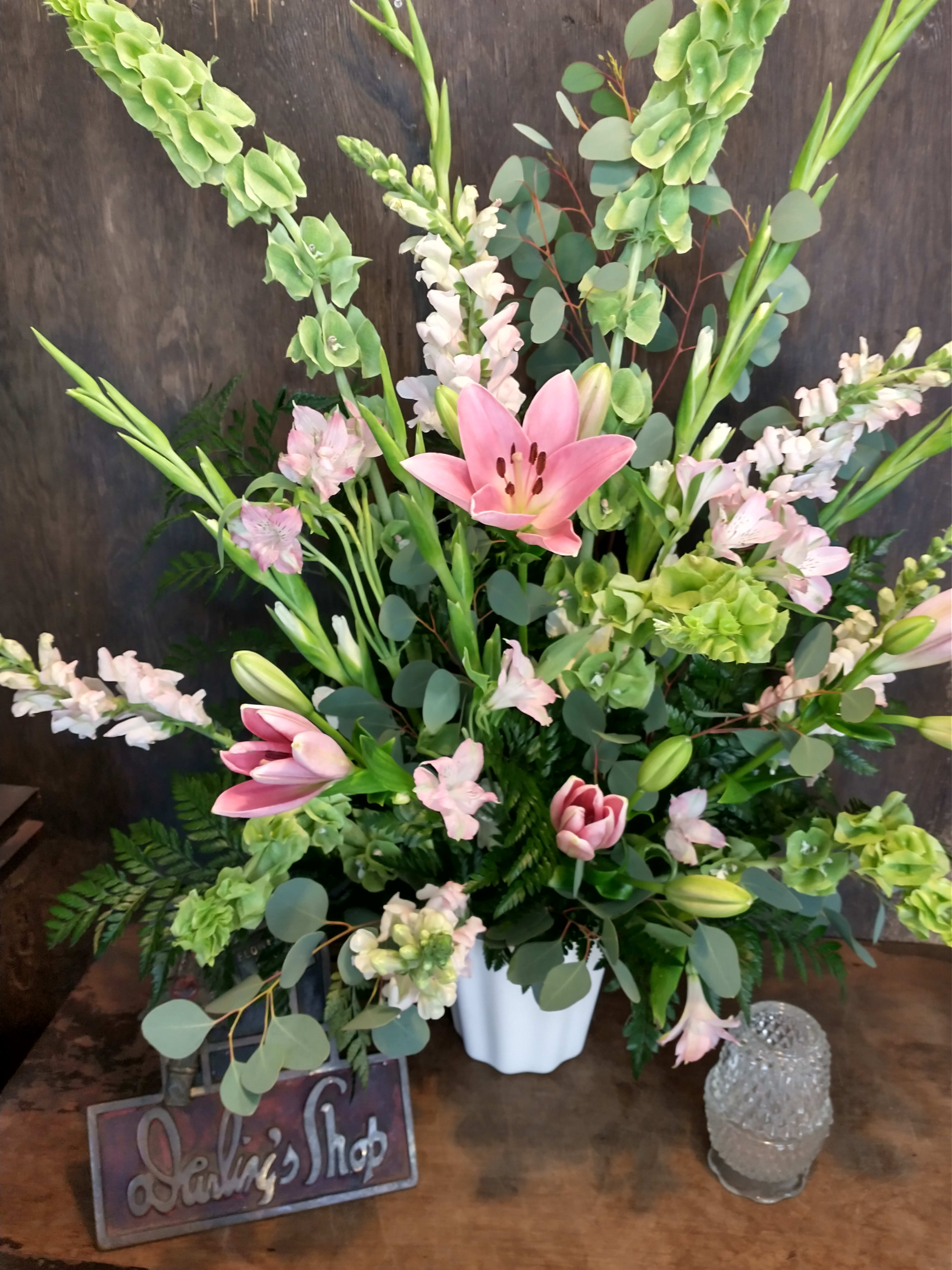 Pink lilies and pale blooms arranged in a white vase