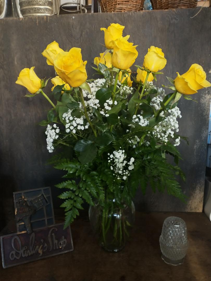 Yellow roses in a clear glass vase with white filler flowers