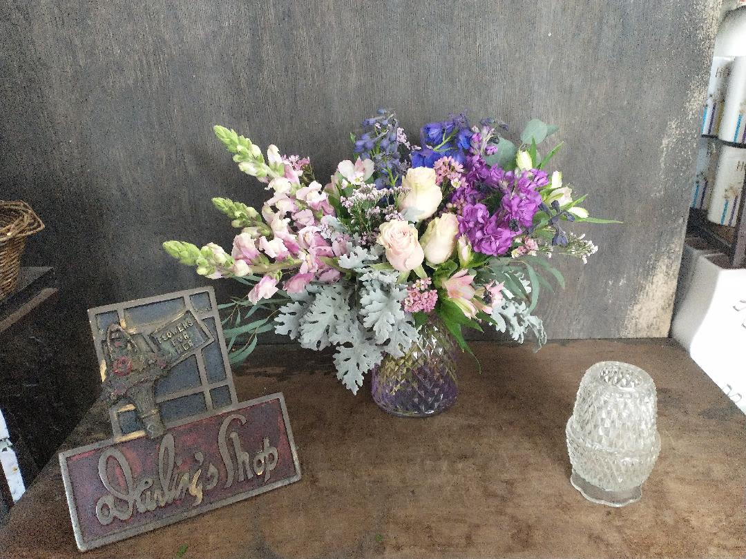 Mixed bouquet of purple, pink, and white flowers in a glass vase