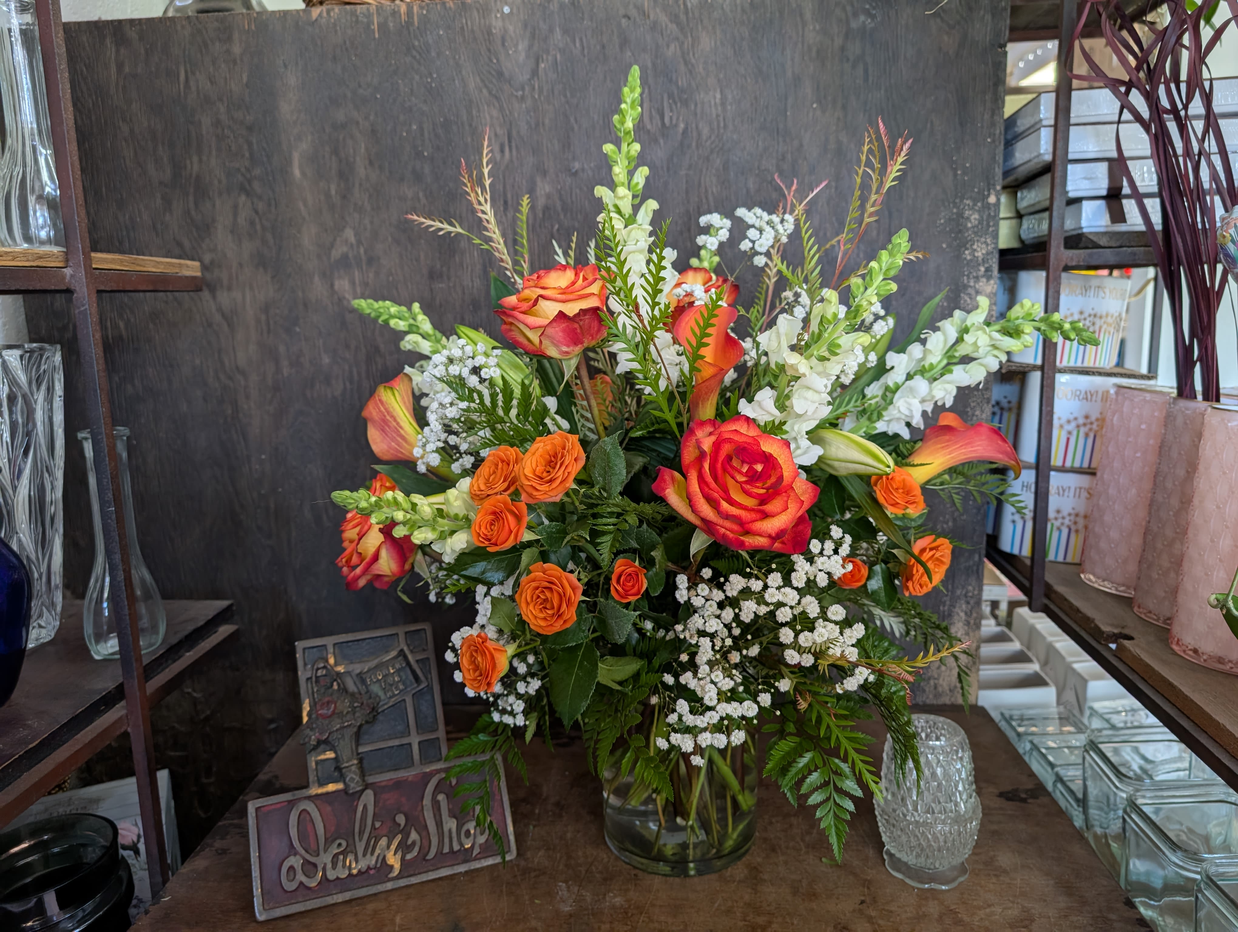 Orange and red roses in a glass vase with white filler flowers