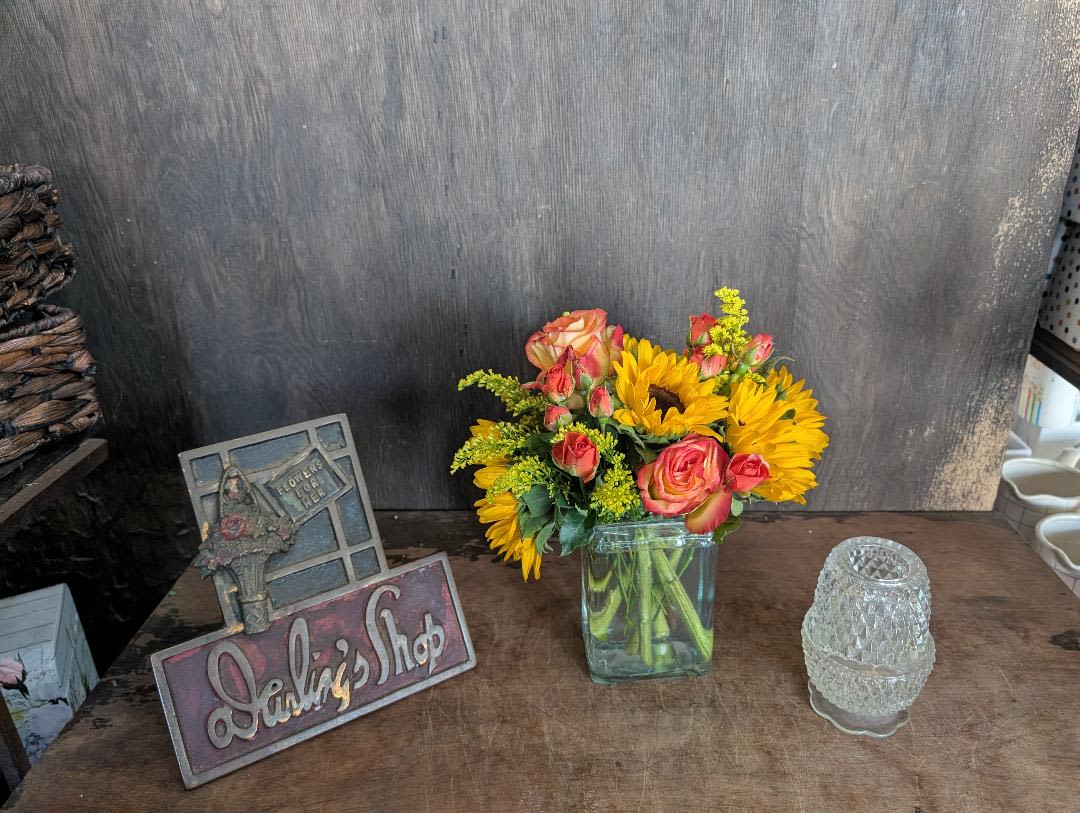 Bouquet of sunflowers and pink roses in a square glass vase