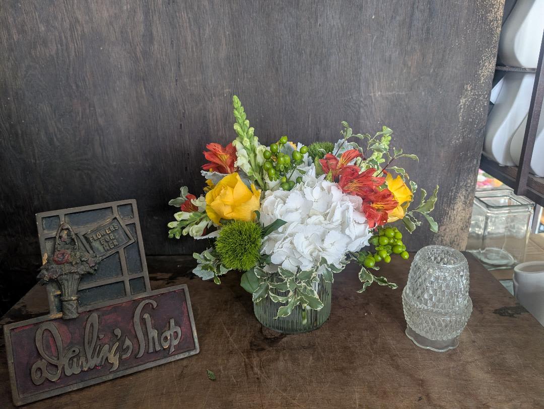 Citrus and More - A bright cluster of white hydrangeas paired with sunny yellow roses and red-orange alstroemeria creates an uplifting everyday flower arrangement perfect for birthdays, thank-you gifts, or a cheerful spring celebration. The tall green snapdragon spike gives a pleasing vertical line while small green berry accents and variegated foliage add texture-so the person you're thinking of will feel genuinely celebrated by its lively, garden-style charm.  